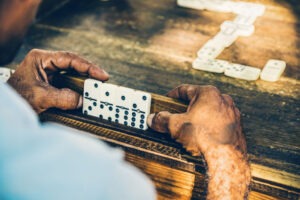 Close-up of hands holding dominoes on a wooden table in a Caribbean setting