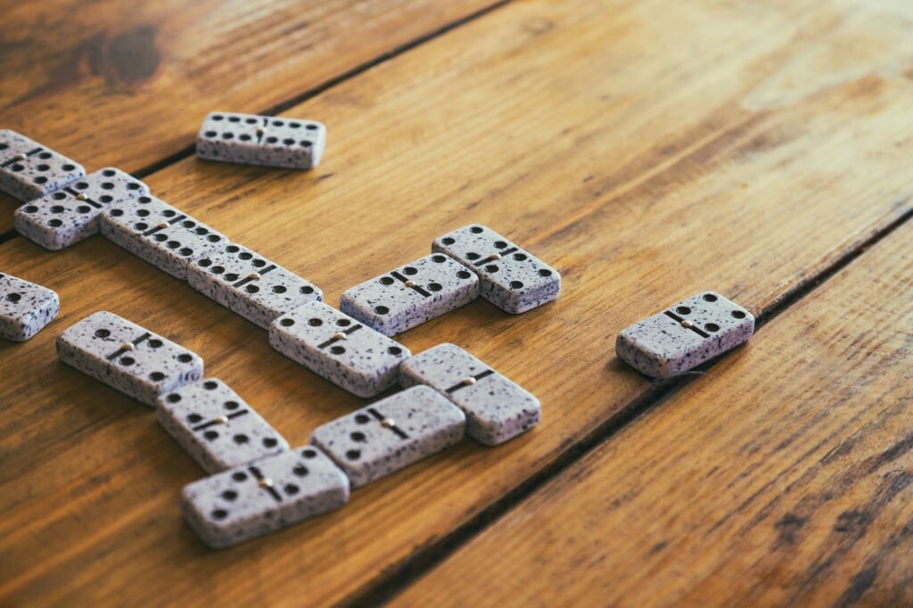 Scattered gray dominoes on a wooden table, depicting a partially played game in a Caribbean setting.