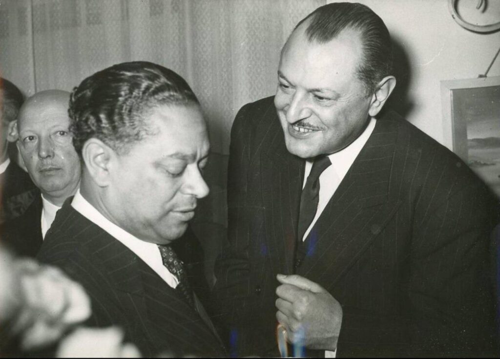Gaston Monnerville talking with a man, both wearing suits