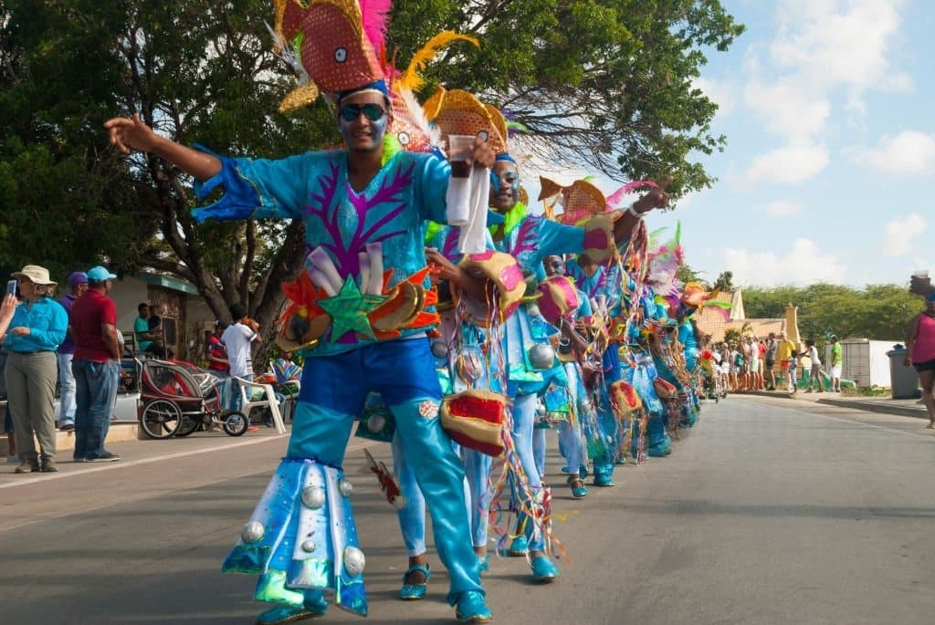 Participants en costumes bleus ornés de poissons colorés défilant dans une rue de Curaçao
