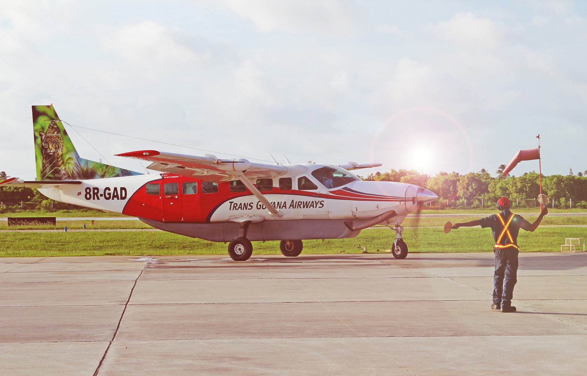 Trans Guyana Airways aircraft 8R-GAD on the runway, guided by a ground crew member