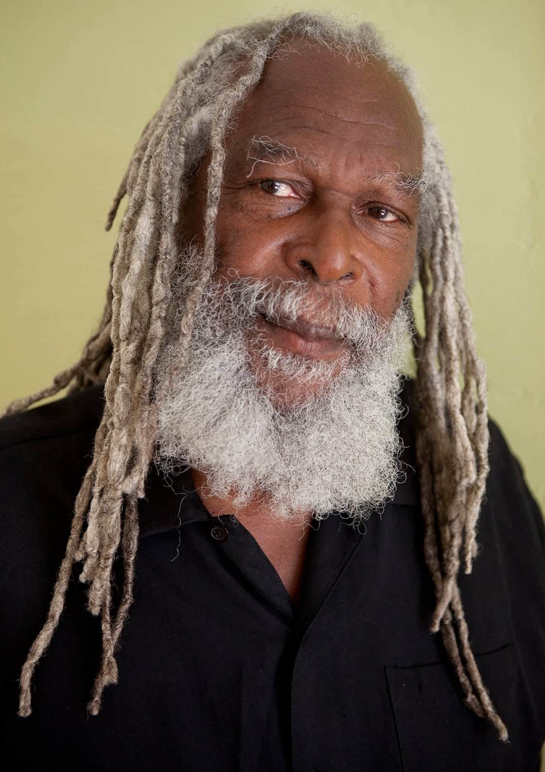 Portrait of Bob Andy, Jamaican singer and songwriter, in front of a green wall